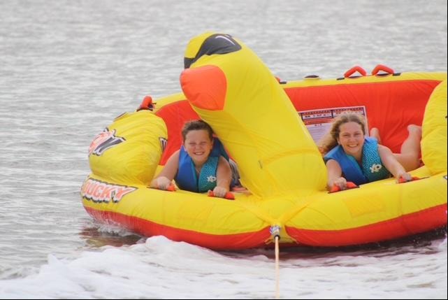 Kids riding the duck tube inflatable on the water